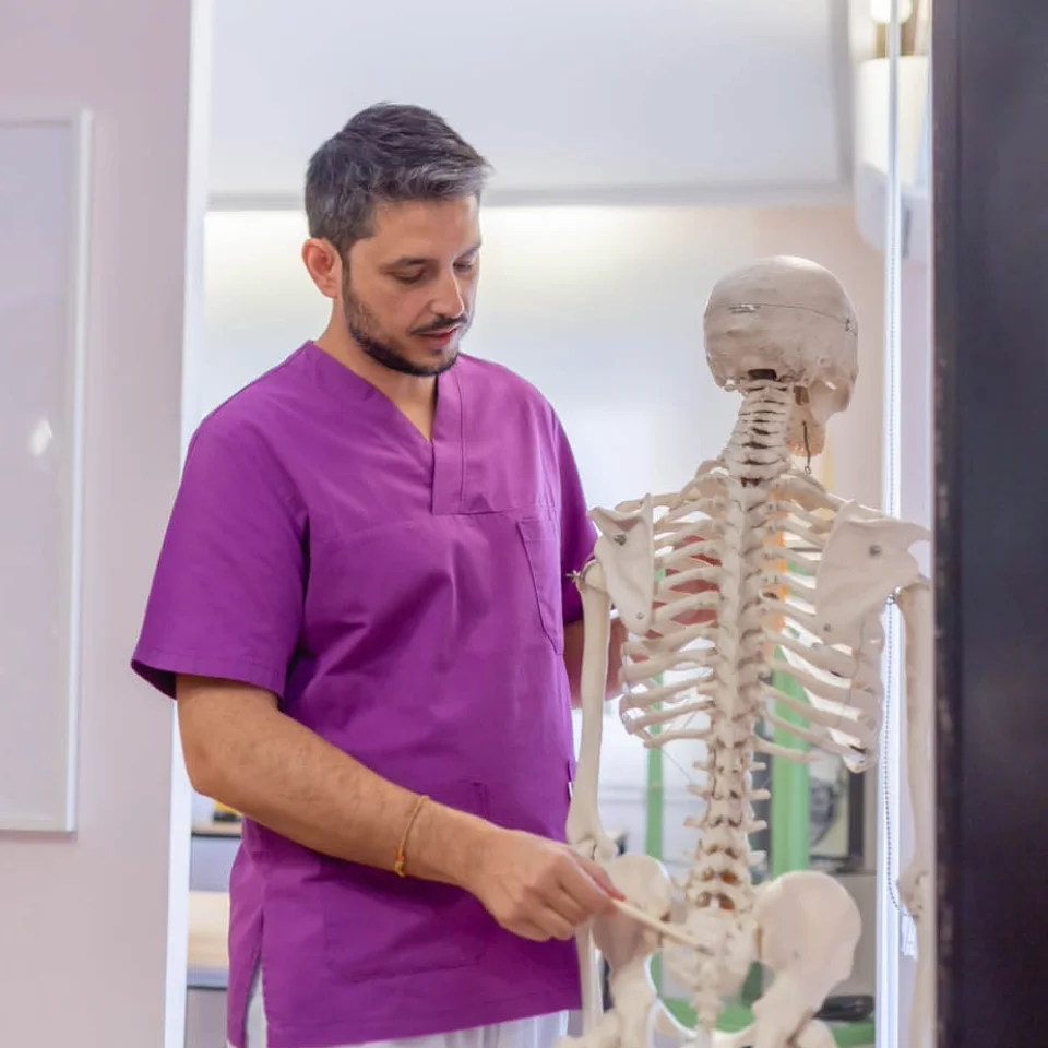 Cuándo acudir a consulta - Fisioterapia Granada Miguel Peña explicando patologías y lesiones articulares sobre un modelo anatómico de columna en Granada